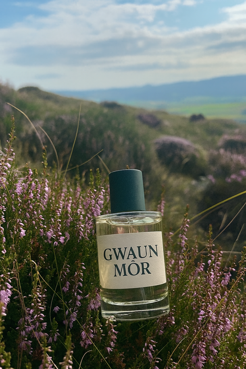 Bottle of Gwaun Mor perfume in a field of purple heather with a scenic background